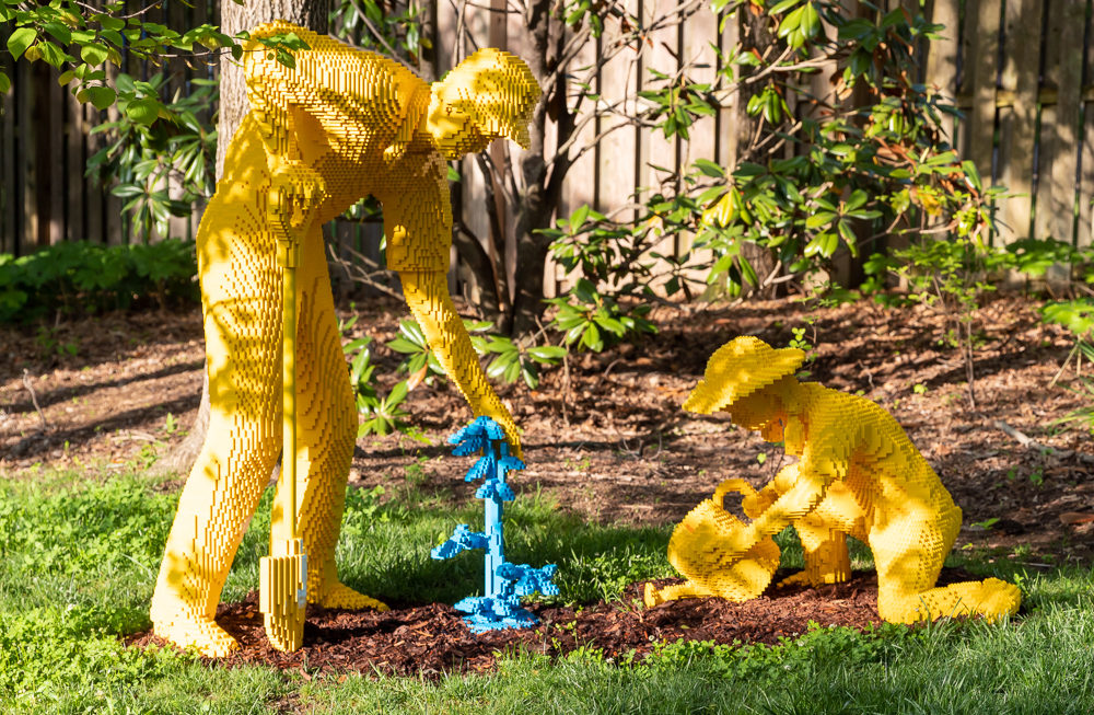 Yellow Lego sculptures of gardeners with a blue fountain of water made from legos