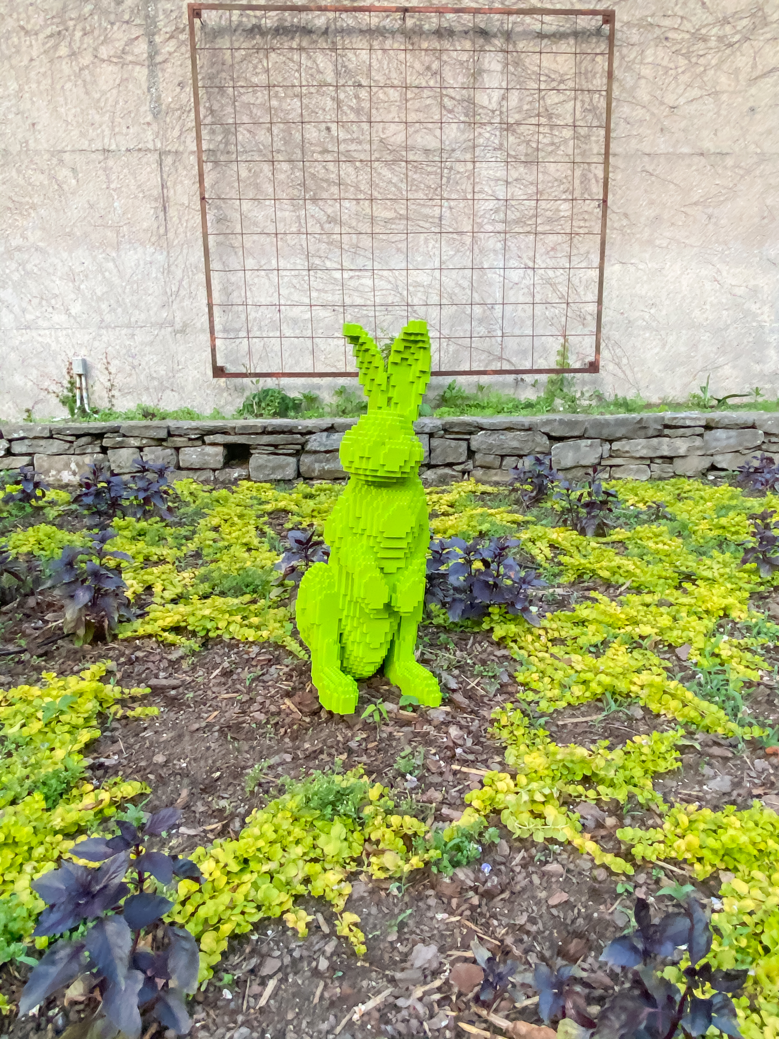 Lime green Lego rabbit surrounded by purple foliage annuals and chartreuse creeping Jenny